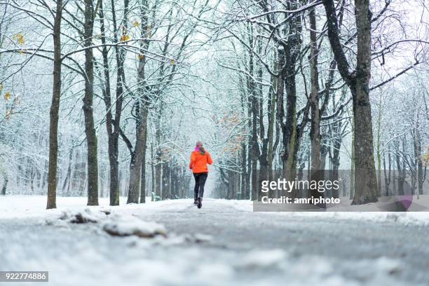 eine frau, die joggen im schneereichen winter gasse rückansicht - prater wien stock-fotos und bilder