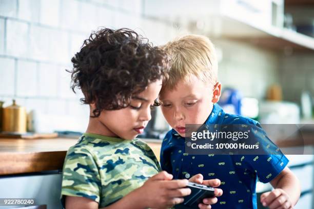 boys playing video game in kitchen - game six stockfoto's en -beelden