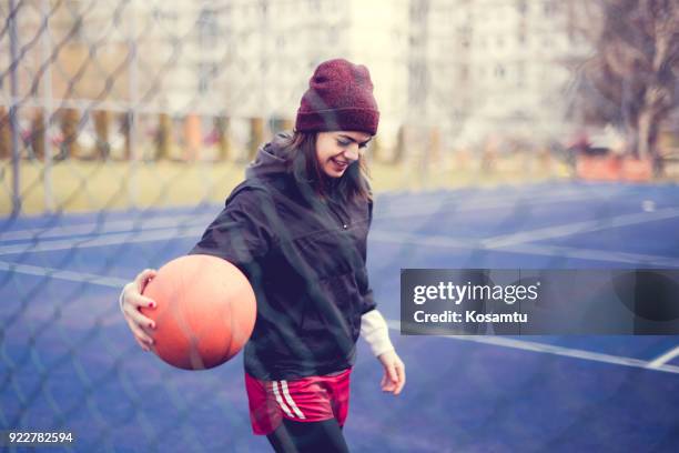 cute girl basket ball op speelveld dribbelen - young man holding basketball stockfoto's en -beelden