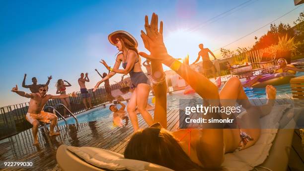 people at pool party dancing and jumping into pool at sunset - poolside stock pictures, royalty-free photos & images