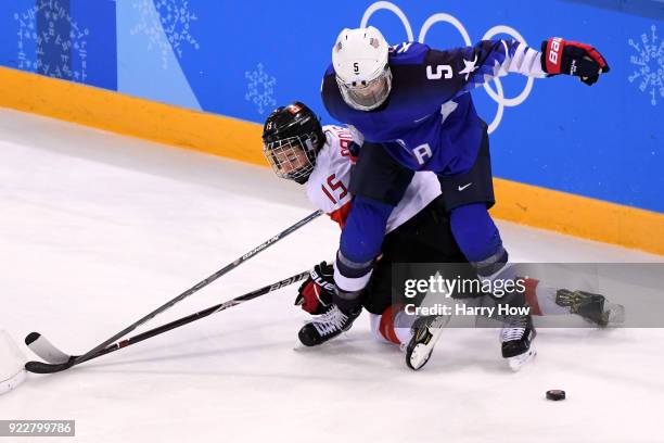 Megan Keller of the United States fights for the puck with Melodie Daoust of Canada in overime during the Women's Gold Medal Game on day thirteen of...
