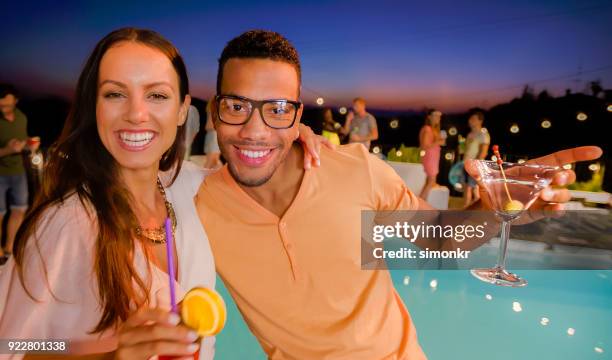 couple posing for photograph at party by pool at night - pool party night stock pictures, royalty-free photos & images