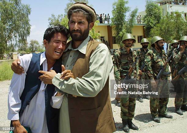 Mourner is consoled as the coffin of assassinated Afghan Vice President Haji Abdul Qadir arrives at Jalalabad Airport July 7, 2002 in Afghanistan....