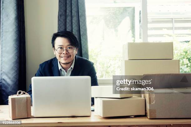 asian business man holding tablet for online shopping with laptop computer and with packaged to be shipped global - quitar fondo de imagen online fotografías e imágenes de stock