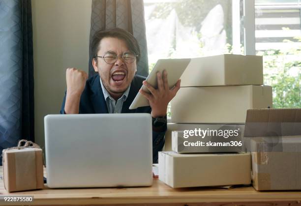 asian business man holding tablet for online shopping with laptop computer and with packaged to be shipped global - quitar fondo de imagen online fotografías e imágenes de stock