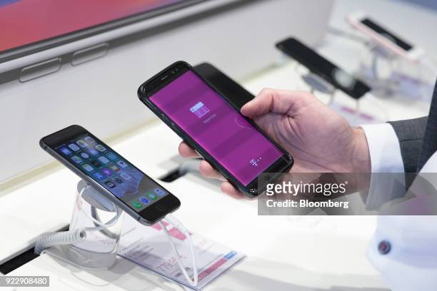An employee holds an Apple Inc. IPhone X smartphone inside the the Deutsche Telekom AG store at the company's headquarters in Bonn, Germany, on...