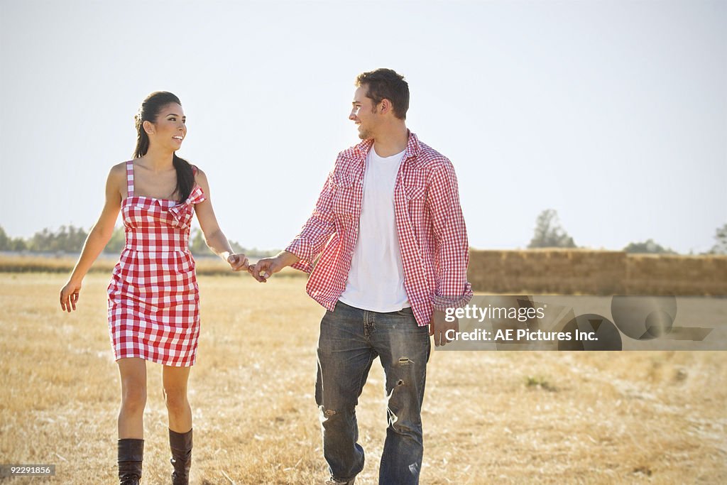 Couple walk on ranch holding hands