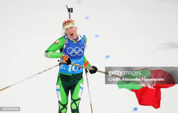 Darya Domracheva of Belarus celebrates with a flag as she approaches the finish line to win gold during the Women's 4x6km Relay on day 13 of the...