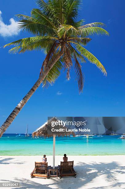 people on lounge chairs under parasols on beach - boracay beach stock pictures, royalty-free photos & images