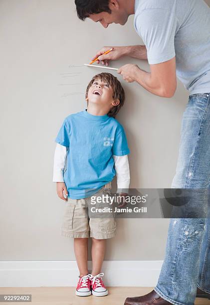 father measuring son's height against wall - height stock pictures, royalty-free photos & images