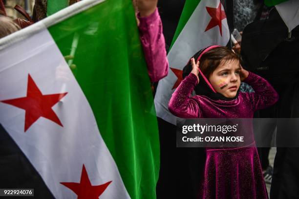 Girl reacts as she stands next to a protester holding a Syrian former independence flag in front of Russian Consulate in Istanbul on February 22,...