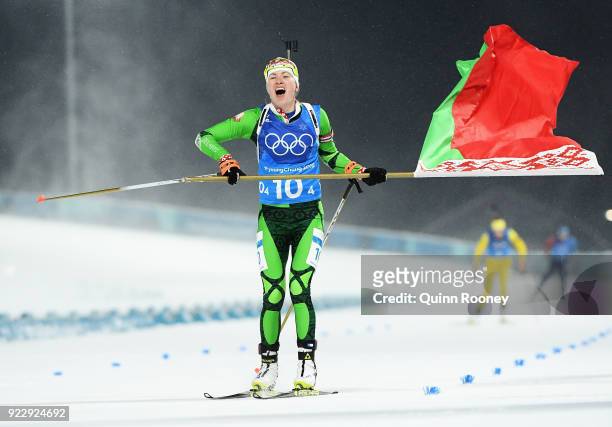 Darya Domracheva of Belarus celebrates with a flag as she approaches the finish line to win gold during the Women's 4x6km Relay on day 13 of the...