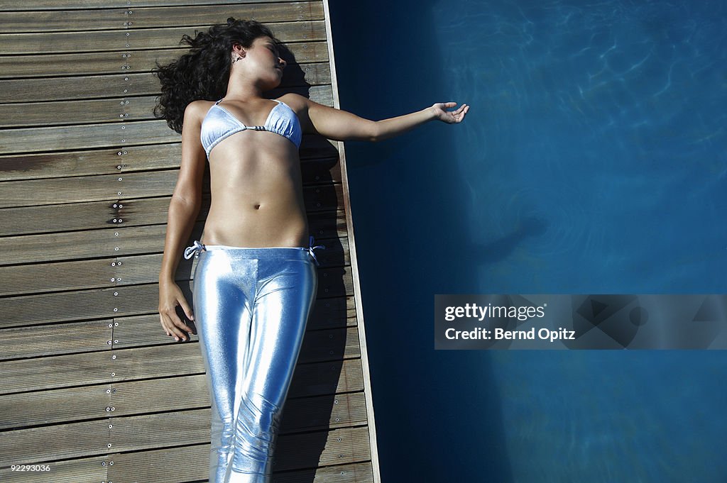 Girl in silver trousers lying on a boardwalk