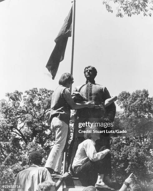 Students wearing hippie attire climb on a statue, possible a Confederate monument, during an anti Vietnam War student protest at North Carolina State...