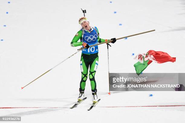 Belarus' Darya Domracheva skis with a Belarus' flag to cross the finish line in the women's 4x6km biathlon event during the Pyeongchang 2018 Winter...