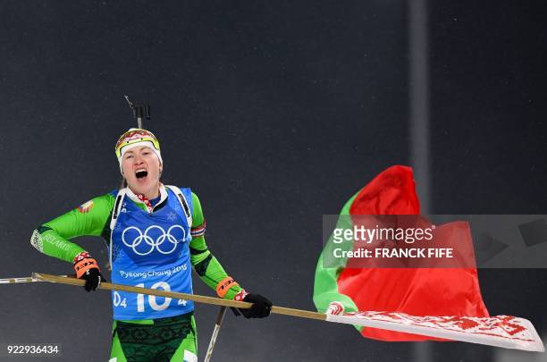 Belarus' Darya Domracheva skis with a Belarus' flag to cross the finish line in the women's 4x6km biathlon event during the Pyeongchang 2018 Winter...