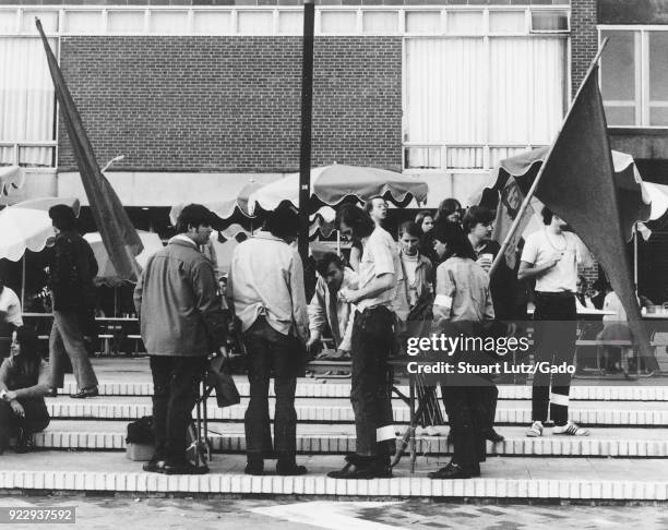 Group of students wearing hippie attire gathers on steps and prepares to raise flags during an anti Vietnam War student sit-in protest at North...