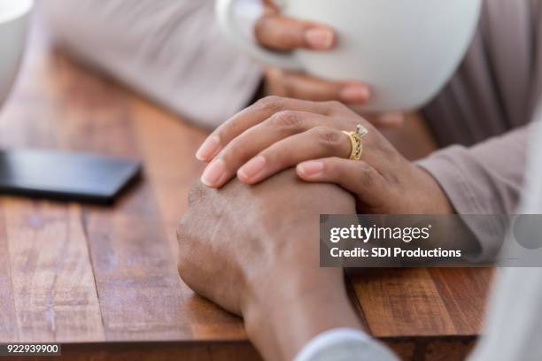 unrecognizable woman consoles husband while in coffee shop - fragile stock pictures, royalty-free photos & images