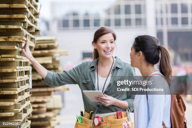 vrolijke ijzerhandel werknemer bespreekt houten pallets met klant - help:category stockfoto's en -beelden