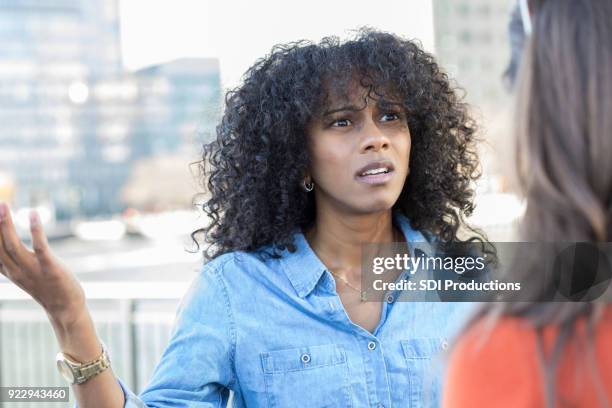 giovane donna litiga con amico su strada città - friends argue foto e immagini stock