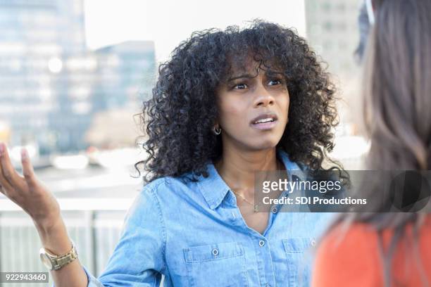 young woman argues with friend on city street - angry black woman stock pictures, royalty-free photos & images