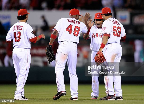Erick Aybar of the Los Angeles Angels of Anaheim celebrates with teammates Maicer Izturis, Torii Hunter, and Bobby Abreu after defeating the New York...