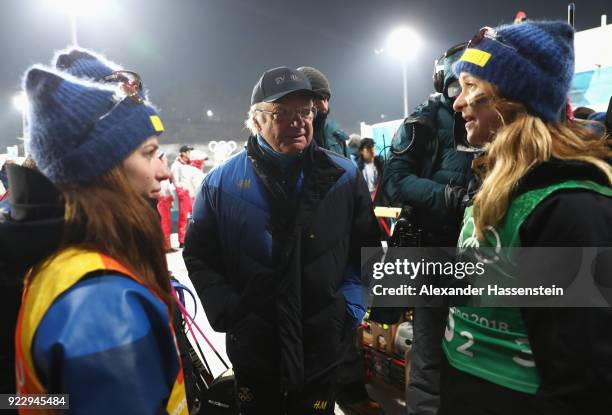 King Carl Gustaf of Sweden celebrates with silver medalists Anna Magnusson and Mona Brorsson of Sweden after during the Women's 4x6km Relay on day 13...
