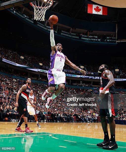 Greg Oden of the Portland Trail Blazers looks on as Amar'e Stoudemire of the Phoenix Suns goes in for a layup during their pre-season game at General...