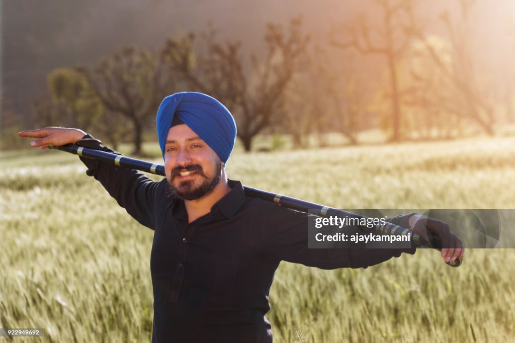 Man holding a stick and smiling in a field