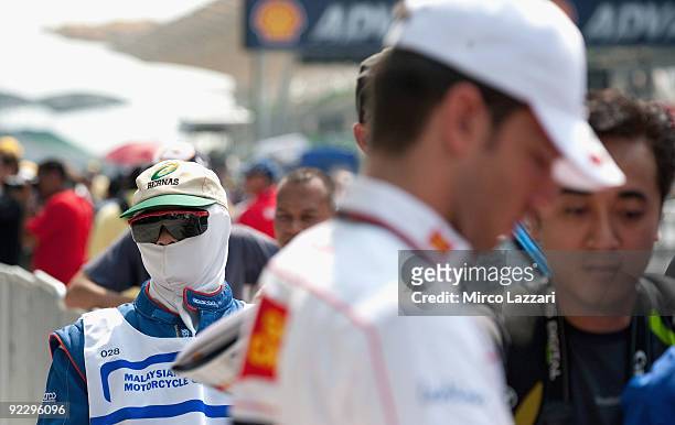 Pit marshall looks on as Alex De Angelis of Rep. San Marino and San Carlo Honda Gresini signs autographs for fans during the pit walk before practice...