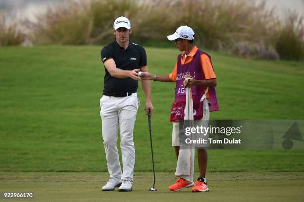 Lorenzo Gagli of Italy takes a ball from his caddie during the first round of the Commercial Bank Qatar Masters at Doha Golf Club on February 22,...