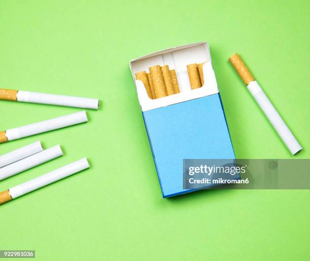 cigarette box and cigarettes on green background - cigarette box stock pictures, royalty-free photos & images