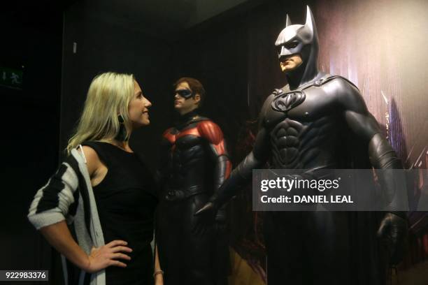 An employee looks at a costume of Batman worn by George Clooney in Batman and Robin designed by Bob Ringwood and Robert Turturice during a press...