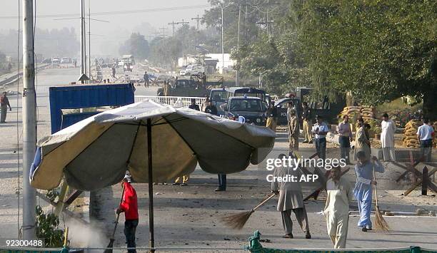 Pakistani security officials secure the site after a suicide bomb attack in Kamra, near the Pakistan Aeronautical Complex on October 23, 2009....