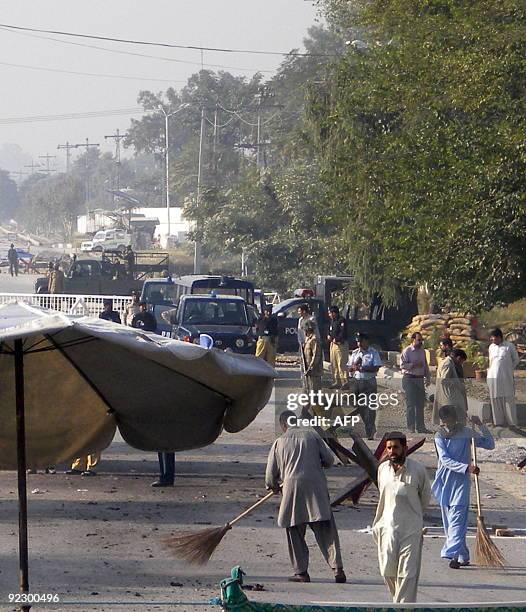 Pakistani security officials secure the site after a suicide bomb attack in Kamra, near the Pakistan Aeronautical Complex on October 23, 2009....