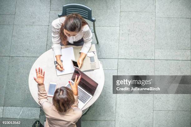 two business women having a meeting at a table outdoors - overhead view meeting stock pictures, royalty-free photos & images