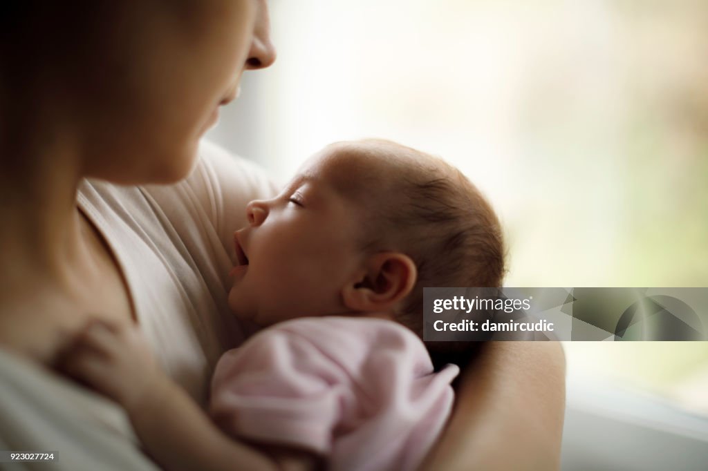 Mother holding her baby girl at home