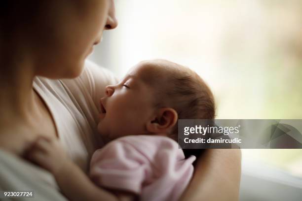 mother holding her baby girl at home - baby bonding stock pictures, royalty-free photos & images