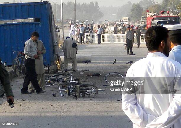 Pakistani security officials inspect the site after a suicide bomb attack in Kamra, near the Pakistan Aeronautical Complex on October 23, 2009....