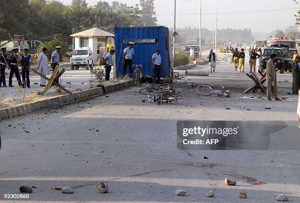 Pakistani security officials inspect the site after a suicide bomb attack in Kamra, near the Pakistan Aeronautical Complex on October 23, 2009....