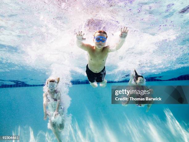 young boy and two young girls jumping into pool - just do it fotografías e imágenes de stock