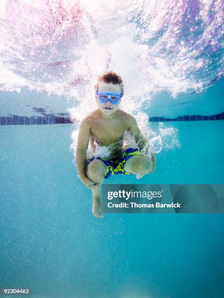 young boy jumping into pool doing cannon ball - arschbombe stock-fotos und bilder