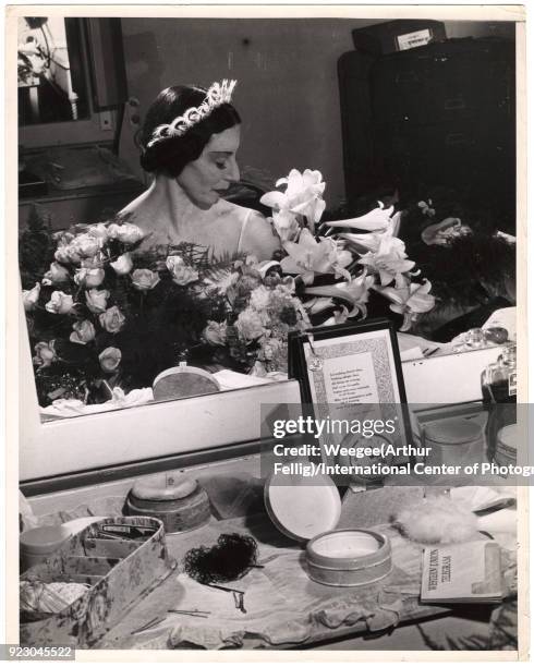 View, reflected in a mirror, of English ballet dancer Alicia Markova backstage in her dressing room, surrounded by flowers, New York, New York, 1950s.