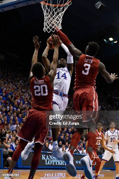 Malik Newman of the Kansas Jayhawks shoots between Kameron McGusty and Khadeem Lattin of the Oklahoma Sooners at Allen Fieldhouse on February 19,...