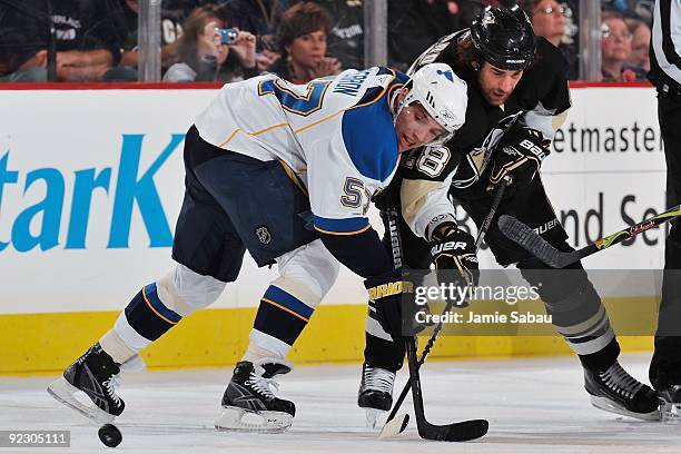 Left wing David Perron of the St. Louis Blues and right wing Eric Godard of the Pittsburgh Penguins battle for a loose puck on October 20, 2009 at...