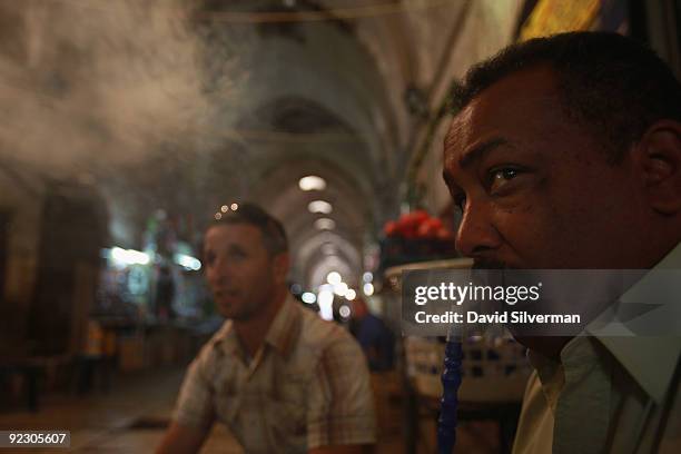 Palestinian man smokes a nargilla water pipe as he sits with frinds at a coffee shop in the vaulted Mamluke-era Cotton Market of the Old City on...