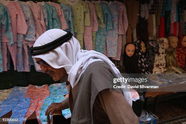 An elderly Palestinian man passes by a stall selling womens' and childrens' clothing in the Muslim Quarter of the Old City on October 22, 2009 in...