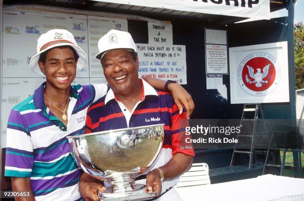 Tiger Woods, age 15 years, six months, and 28 days, and father Earl Woods, pose for a photo while celebrating Tiger's victory at the 1991 USGA Junior...