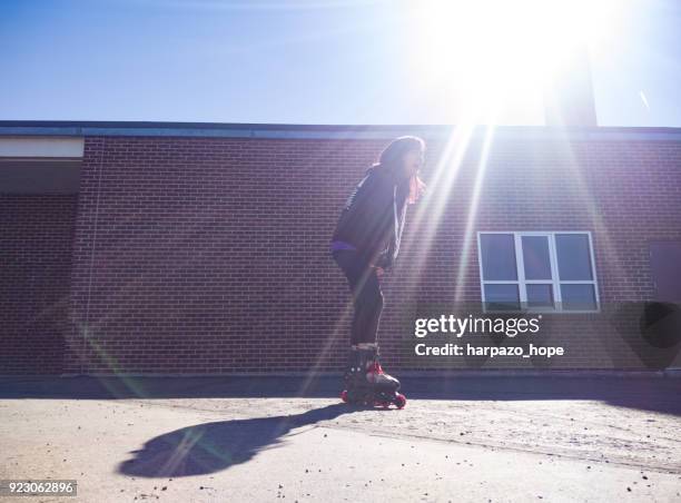 teenage girl rollerblading by a brick building. - harpazo hope stock pictures, royalty-free photos & images