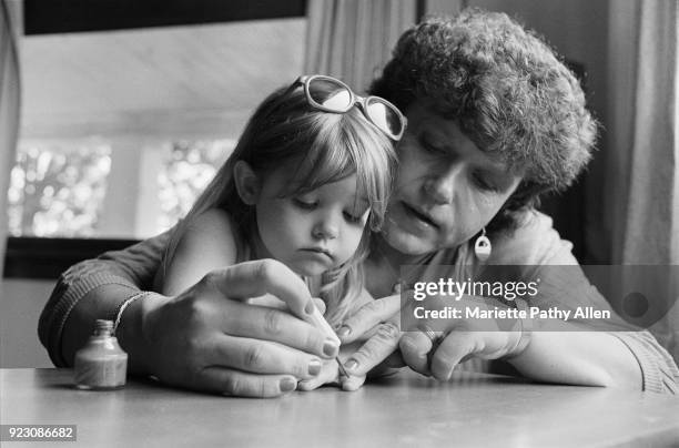 Elayne with Daughter Sally, Painting Twenty Nails Pink", an image from the book “Transformations" by Mariette Pathy Allen, which documents the lives...